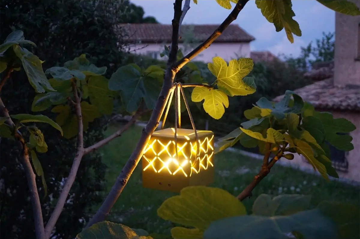 Maiori La Lampe Popup solar garden light hanging from a tree branch at dusk, ideal for ambient outdoor lighting in Dubai gardens.