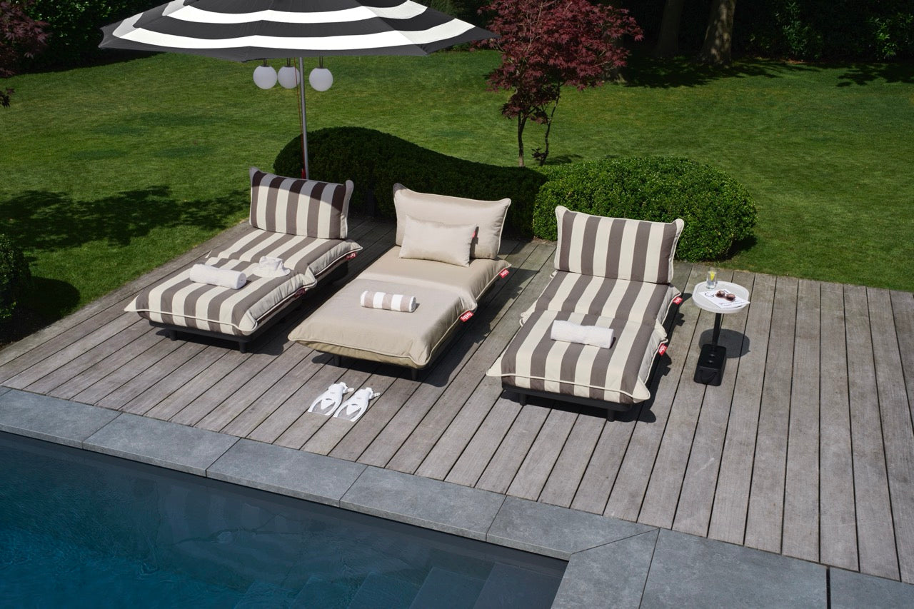Pool deck featuring the new Fatboy Paletti modular sofa in stripe cacao, with Stripesol parasol, and Bolleke hanging lights.