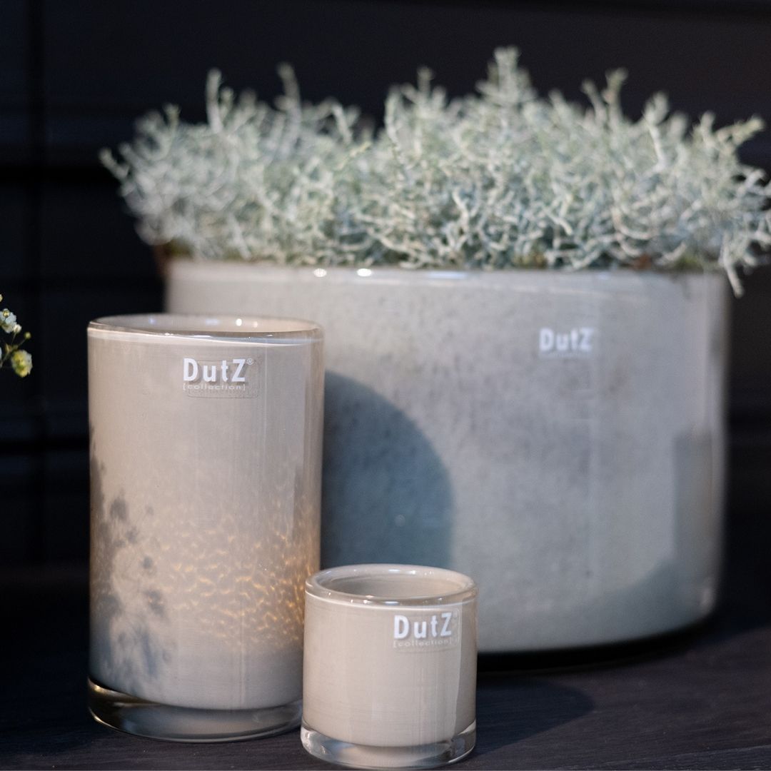 DutZ votive candle holders in all three sizes, displayed with a large beige DutZ vase holding yellow blooms.
