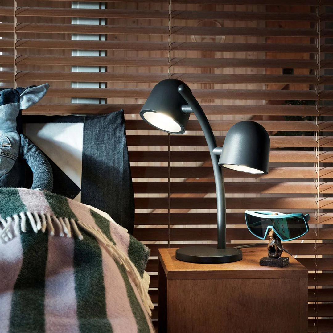 Fatboy Little Lebow lamp in matte black, shown on a wooden bedside table with soft ambient lighting.