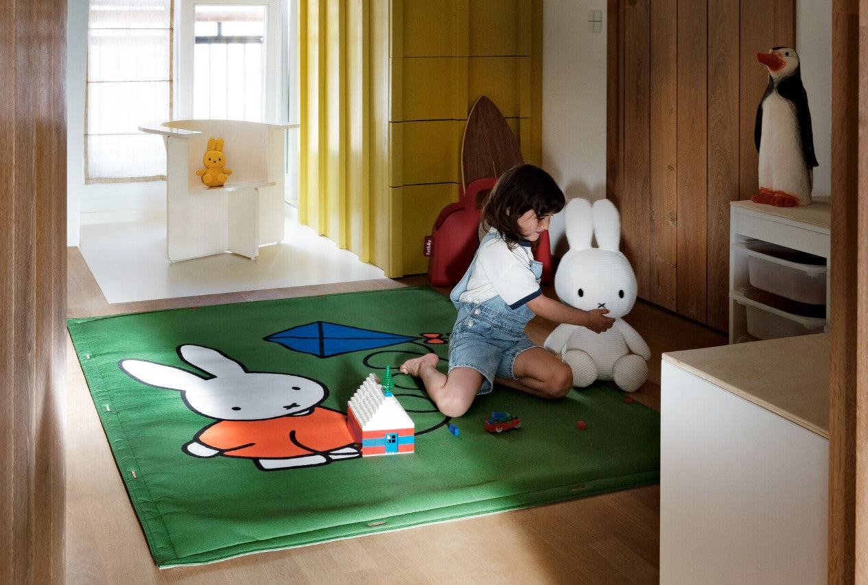 Child playing with a Miffy stuffed toy with the Flying Carpet x Miffy outdoor carpet serving as a defined playtime zone.