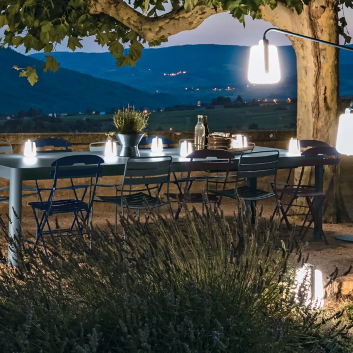 Fermob Balad mini table lamps glowing on an outdoor dining table.
