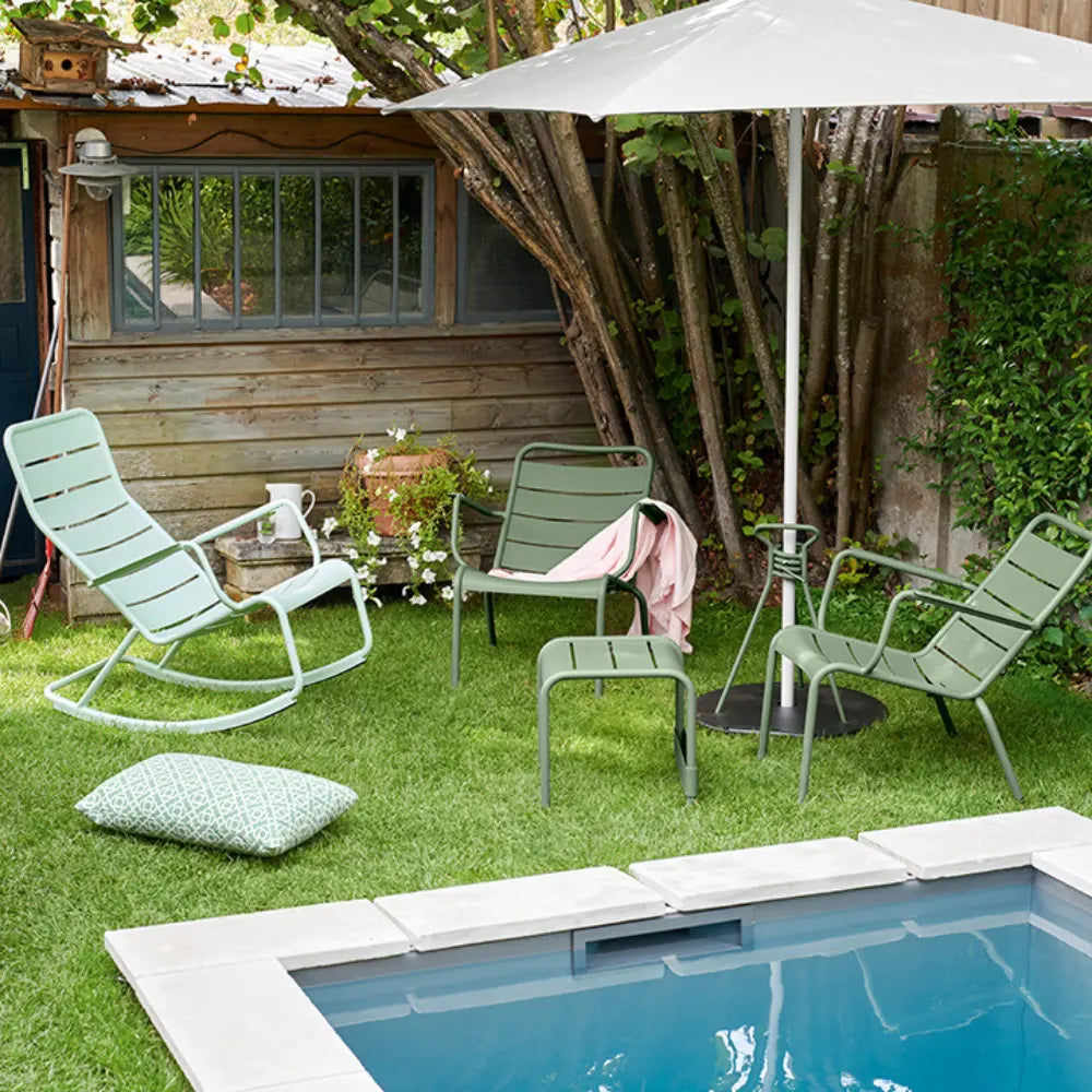 Fermob Luxembourg low armchairs and pillow styled as an outdoor lounge setup by the pool.