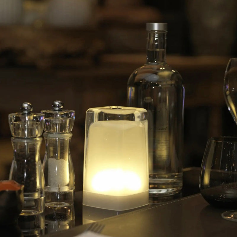 Imagilights modern table lamp glowing softly on a restaurant table setup, used as ambient lighting or a cordless desk lamp for versatile spaces