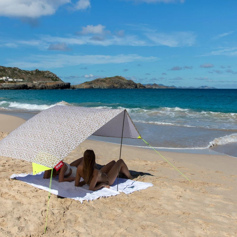 Women relaxing under a propped-up Fatboy Miasun Beach Tent together with the Beach Buggy towel.