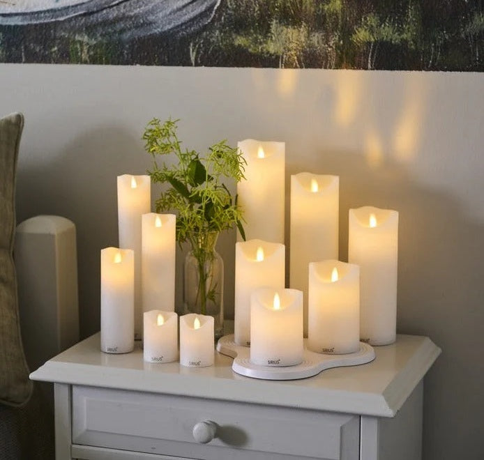 A set of Sirius Sara rechargeable LED candles in white placed atop a side table. 