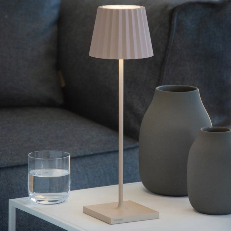 Sompex modern table lamp in beige used as a stylish desk lamp on a white side table in a contemporary living room setup