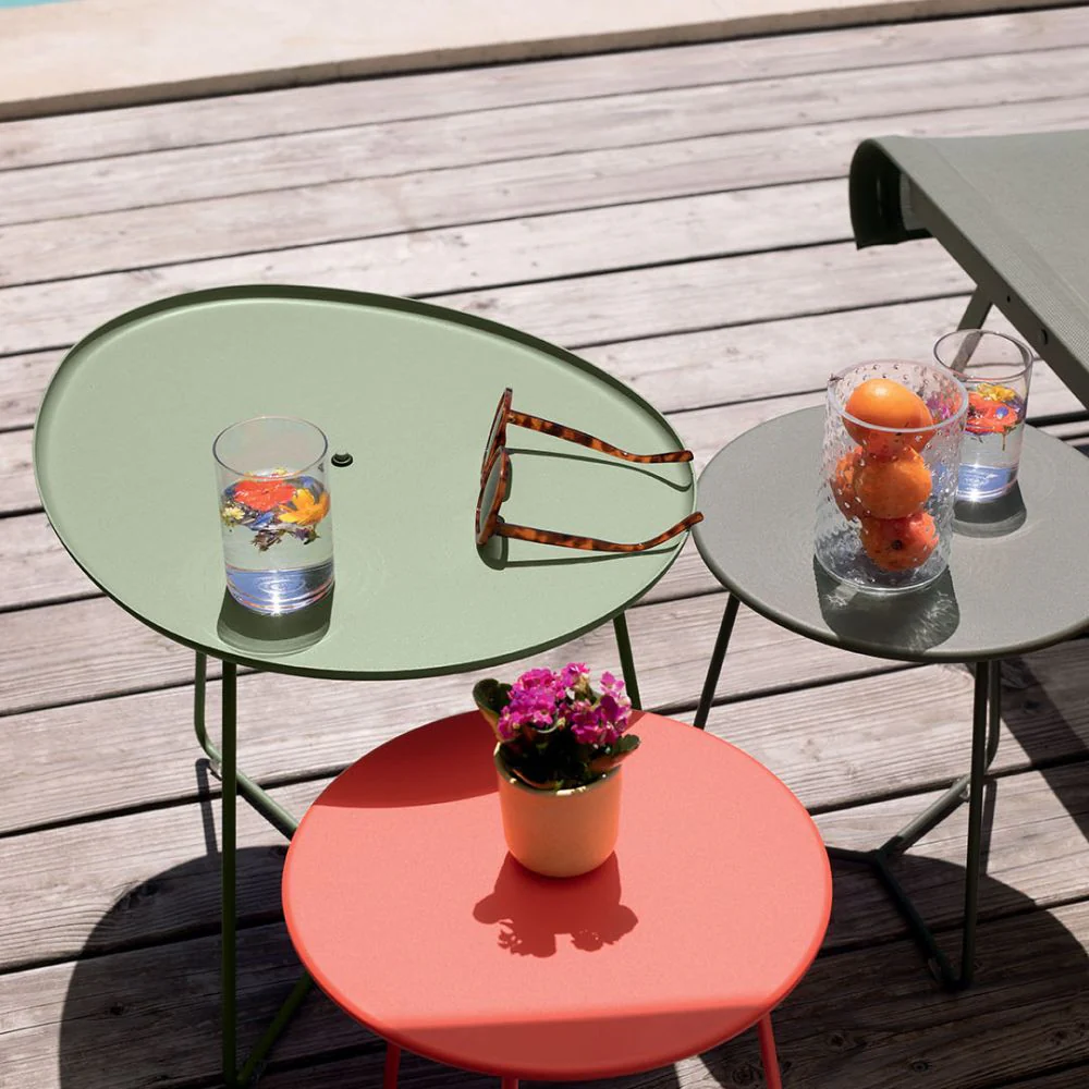 A trio of Fermob Cocotte low stools and side tables in various shapes creates a colourful, functional display of side tables for outside.
