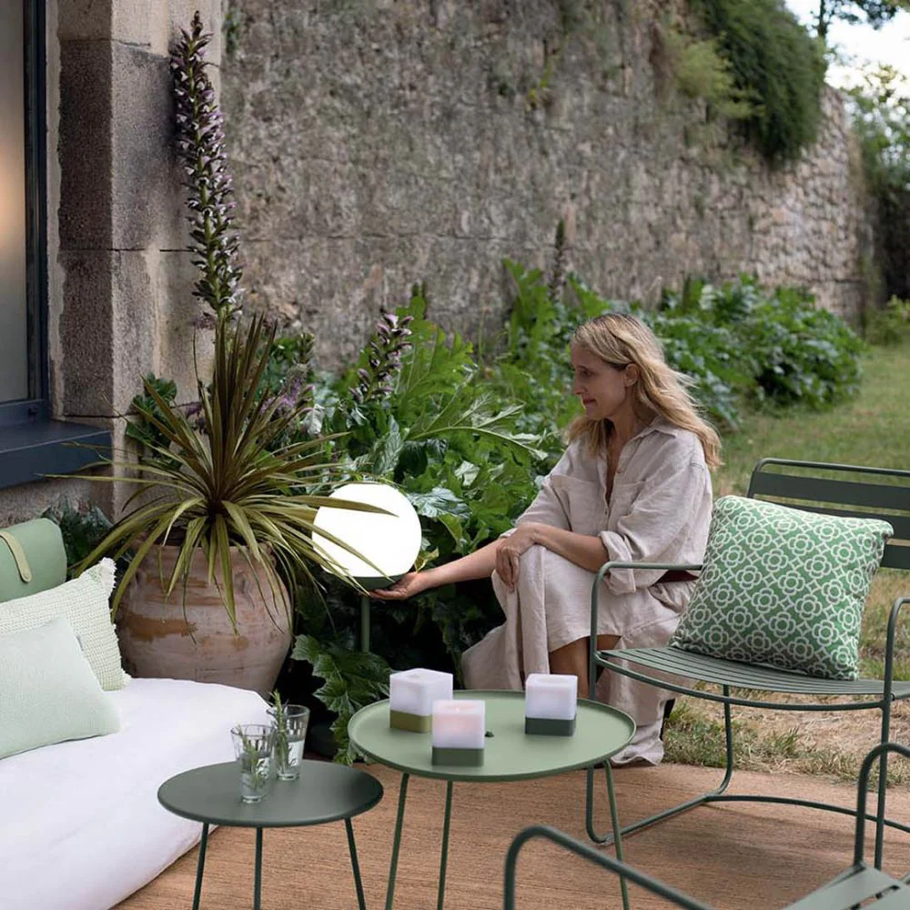 The Fermob Cocotte low table is shown as an elegant outdoor side table, perfect for garden nooks.
