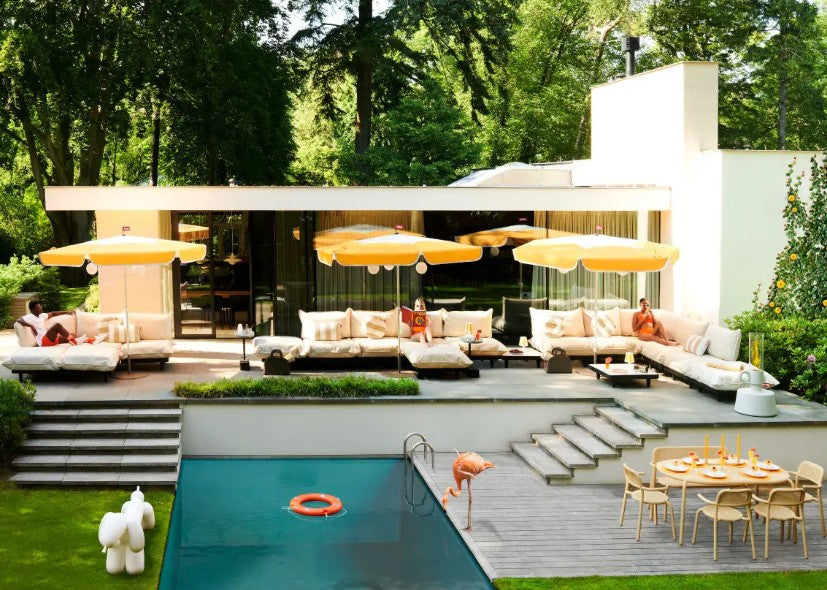 An outdoor garden space decorated Fatboy Sunshady parasols, lounge seating, and Toni Tavolo dining tables and armchairs.